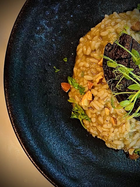 Saffron risotto with a portobello mushroom and pea shoots in a dark blue bowl