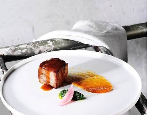 A glazed square of pork belly with an orange purée and pickled onion