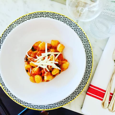 Gnocchi in tomato sauce topped with grated ricotta salata on a patterned plate
