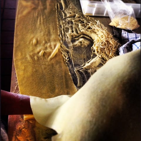 A sheet of fresh egg pasta draped over a carved wooden board