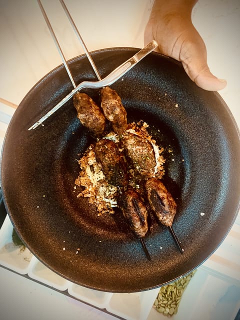 Glazed lamb skewers being served in a dark bowl